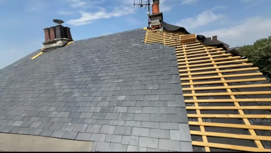 Toiture en ardoise en cours de pose à Bois-Guillaume, avec deux souches de cheminée et des liteaux posés sur l'écran de sous-toiture visibles sur la droite